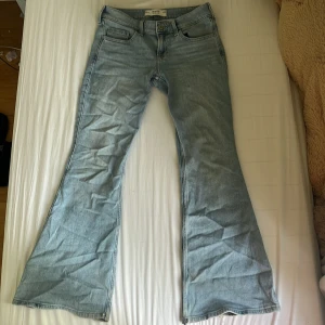 Low waist Flare Jeans från Hollister - Snygga ljusblå jeans från Hollister med låg midja och utsvängda ben. Dom är slitna längst ner på benen (se sista bilden). Säljer då dom är för stora för mig!