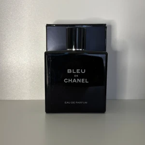 Bleu de Chanel Eau de Parfum - Stilren och lyxig parfym från Chanel i en mörkblå, fyrkantig glasflaska med silverfärgad kork. Flaskan har tydlig vit text och ger en exklusiv känsla. Perfekt för dig som gillar eleganta och moderna dofter.