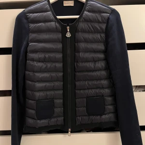 Superfin Moncler Cardigan i marinblå - Säljer nu min superfina Moncler cardigan i marinblå, storlek S. Sparsamt använd men finns tecken på användning, tex vid lappen i nacken. QR kod finns för att visa äktheten, men har tyvärr inget kvitto eller så. SKRIV TILL MIG INNAN KÖP!🤎