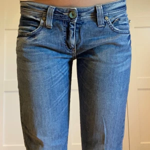 Blå bootcut jeans från Big Star - Snygga blå jeans från Big Star med klassisk femficksdesign och raka/bootcut-ben. Jeansen har låg midja, slitna detaljer och en cool knapp framtill. Perfekta för dig som gillar en avslappnad men ändå trendig look. De är lite för korta på mig som är 164cm. 