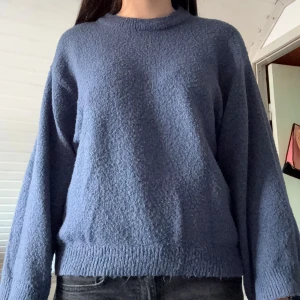 Blå stickad tröja från 157 - Mysig blå stickad tröja från 157 i storlek XS. Tröjan har en enkel design med rund halsringning och ribbade muddar vid ärmslut och nederkant. Perfekt för lager-på-lager och chill dagar.