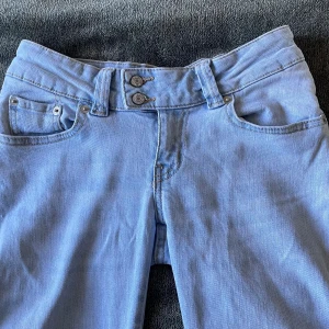 Ljusblå bootcut jeans  - Säljer ett par ljusblå jeans med bootcut-modell och snygga dubbla knappar i midjan. Jätte lågmidjade och i nyskick. 