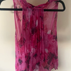 As snygg festtopp från zara 💘 - Säljer en transparent blommig blus i starka rosa toner med plisserad front. Blusen är ärmlös och har ett luftigt, flowy fall. Perfekt för dig som gillar färg och vill sticka ut med ett romantiskt mönster. Passar snyggt till både jeans och kjol. Köpt för 40€ så säljer också för lite dyrt pris då det är i perfekt skick! Använd max 5 gånger💘💘 är 174 cm lång och den passar perfekt