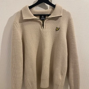 Beige stickad quarter zip från Lyle & Scott - Säljer en stickad quarter zip från Lyle & Scott. Tröjan har används lite och har inga synliga defekter. Passar perfekt nu inför vintern eftersom att den är väldigt varm.