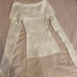 Vit ribbad offshoulder topp  - Supersnygg vit ribbad offshoulder topp från BikBok i storlek XS. Toppen har långa ärmar och en bred krage som sitter snyggt över axlarna. Materialet är stretchigt och sitter tajt mot kroppen.