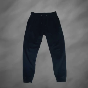 Svarta mjukisbyxor med snörning - Svarta mjukisbyxor med resår och snörning i midjan. Byxorna har muddar vid bensluten och är perfekta för chill dagar eller träning. Mjukt material som känns skönt mot huden.