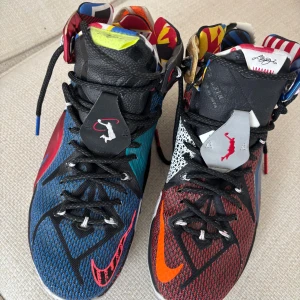 Nike LeBron 18 Multicolor Sneakers - Unika Nike LeBron 18 sneakers med färgstark design – ena skon är blå och svart med röda detaljer, andra skon är röd och svart med orange Swoosh. Skorna har mönstrad plös i rött, vitt, gult och blått, samt signaturdetaljer och snörning. Ovandel i mesh och syntet, med coola kontraster och grafik.