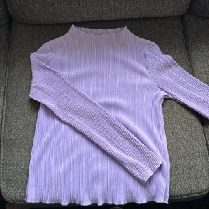 Ljuslila ribbad långärmad tröja Bikbok storlek M - En ljuslila långärmad tröja från Bikbok i storlek M. Tröjan har ett ribbat tyg. Modellen är rak med högre hals och stretchigt material som sitter skönt. 