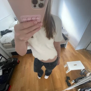Vit ribbad croppad topp med pärldetalj - Superfin beige croppad topp med kort ärm och ribbad struktur. Toppen har en vågig nederkant dekorerad med små pärlor och säljs då den aldrig kommer till användning💓