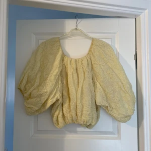 Zara Gul volangblus  - Supersöt gul blus från Zara med stora puffärmar och volangig, luftig passform. Blusen har rund halsringning och är gjord i ett lätt, stickat material med spetskänsla. Perfekt för dig som vill sticka ut med en unik och trendig topp!