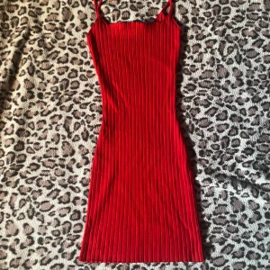 Röd kort klänning  - Supersnygg röd ribbad klänning från Bershka i figurnära modell. Klänningen är kort med smala axelband och har en stretchig, stickad känsla. Perfekt för dig som gillar en enkel men ändå iögonfallande look. Säljes i storlek XS. Endast testad.
