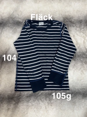 Randig långärmad tröja Polarn O. Pyret - Mörkblå och vit randig långärmad tröja från Polarn O. Pyret. Klassisk design med rund hals och mjuka muddar vid ärmslut. Perfekt för lek eller chill dagar. 🌸 Fläck. Storlek 104