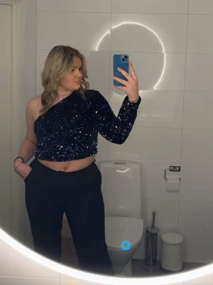Svart glittrig one shoulder topp - Säljer en svart glittrig croppad topp med paljetter. Toppen har oneshoulder-design med en lång ärm. Använd 2 gånger så den är som ny. Nypris runt 1500kr. Säljer för 500. Vid snabb affär kan pris diskuteras 