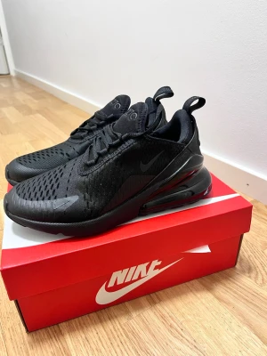 Nike Air Max 270  - Nike Air Max 270 sneakers i helsvart med mesh-överdel och stor synlig Air-enhet i hälen. Skorna har snörning, rund tå och en chunky sula för extra komfort. Perfekta för dig som gillar sportig stil och vill ha något som sticker ut. Säljer pga av att de är små på mig. Kunde inte returnera de eftersom jag var utomlands !