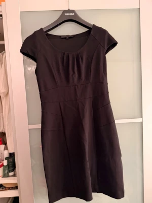 Svart kortklänning från Stockh LM - Säljer en svart kortklänning från Stockh LM i klassisk modell med rundad halsringning och korta ärmar. Klänningen har en figurnära passform upptill och lätt utställd kjol. Perfekt till dig som gillar stilrena och tidlösa plagg.