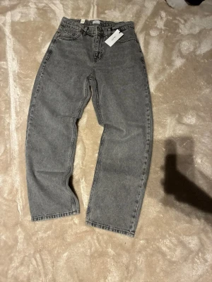 Grunt jeans HELT NYA - Säljer ett par grå jeans från GRUNT i rak modell. Jeansen har klassisk femficksdesign, knappgylf och bälteshällor. Materialet är robust denim i en snygg tvättad grå färg. Perfekta för dig som gillar en enkel och clean look.