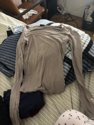 Beige långärmad topp i bomull - En enkel och stilren beige långärmad topp med rund halsringning. Tillverkad i mjuk bomull som känns skön mot huden. Perfekt att matcha med jeans eller kjol för en avslappnad look.