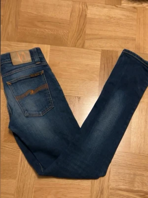  Nudie Jeans - Tjena!! Säljer ett par mörkblå  jeans från Nudie Jeans med klassiska kontrastsömmar och broderade bakfickor. De är tillverkade i mjukt jeansmaterial. Perfekta för dig som gillar en smal passform och stilrena detaljer. Hör av er vid frågor!