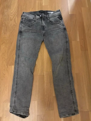 Replay Anbass grå jeans - Säljer ett par Replay Anbass jeans i tvättad grå färg med svarta detaljer och Replay-logga på myntfickan. Jeansen har slim fit passform och är tillverkade i mjukt jeansmaterial med lite stretch.