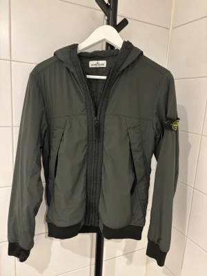 Grön vindjacka från Stone Island Junior - Säljer en grön vindjacka från Stone Island junior strlk 156 passar upp till 163 ish! Jätte fin jacka inga defekter använd 2-3 gånger! Köpt NK Sthlm 