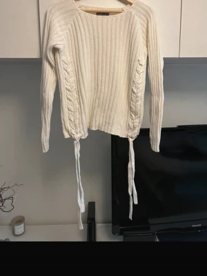 Vit stickad tröja med snörning  - Säljer min supersnygga vita stickad tröja i storlek S. Tröjan har coola snörningsdetaljer längs sidorna💕💕