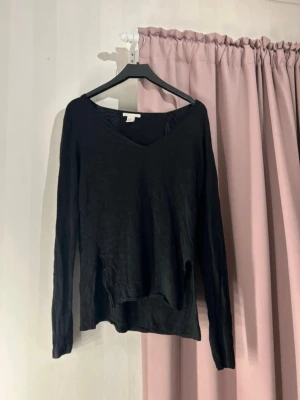 Svart långärmad topp från H&M - En enkel svart tunn stickad tröja från H&M i storlek XS. Toppen har v-ringning och är tillverkad i ett tunt, mjukt material som känns skönt mot huden. Passformen är normal och toppen är perfekt att styla med jeans eller kjol.