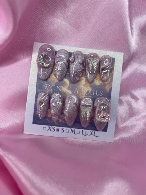 Faye (S);Medium Almond - Set med dirtypink glittriga press-on naglar i medium almondform, dekorerade med silverdetaljer som fjärilar, stjärnor, måne, pärlor och kristaller. Naglarna har coola 3D-accessoarer och passar dig som gillar statement-naglar med unik vibe.S: 15 mm, 11,5 mm, 12 mm, 11 mm, 9 mm 