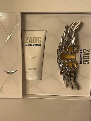 Zadig & Voltaire parfymset - Zadig & Voltaire med unik 50ml flaska och medföljande body lotion 50ml.  Parfymen är endast test sprayad. Bodylotion är oöppnad och otestad. Köpt på notino. Bara parfymen på 50ml kostar 899kr på notino. 
