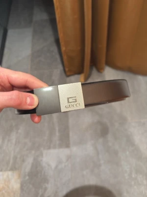 Gucci skärp - Säljer ett svart skärp från Gucci med stilrent, fyrkantigt metallspänne i silverfärg. Skärpet är gjort i slätt skinn och har en klassisk design som passar till många olika outfits. Perfekt accessoar för att lyfta din look.
