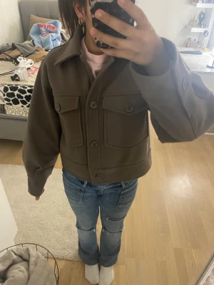 Brun overshirt med stora fickor - Säljer en brun overshirt med stora bröstfickor och knappar framtill. Jackan har en boxig, oversized passform och är gjord i ett tjockare material som känns mjukt. Perfekt för lager på lager och har klassisk krage samt långa ärmar med knappdetalj vid mudden.