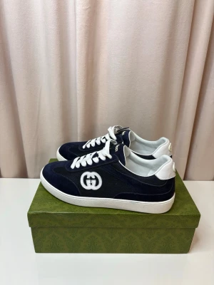 GG sneakers - Säljer ett par marinblå sneakers från Gucci med vit sula och vita detaljer. Skorna har en kombination av mocka och mesh, vita snören och det klassiska GG-logotypen på sidan. Insidan och hälen är i vitt skinn för extra kontrast. Box och dustbag medföljer.