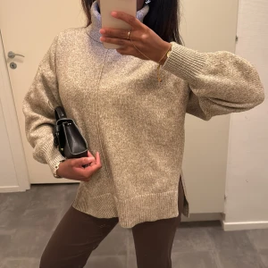 Stickad polotröja med slits - Supermysig beige stickad polotröja med breda muddar och slitsar i sidorna. Tröjan har en loose fit och höga ribbade detaljer vid ärmslut och nederkant ❄️🍂