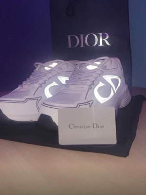 Vita sneakers - Säljer ett par riktigt snygga sneakers i vitt och grått. Skorna har reflekterande detaljer, meshpaneler och skinnpartier. Tjock sula och rund tå ger en modern vibe. Klassisk logga på sidan och plös. Perfekta för dig som vill sticka ut med exklusiva sneakers.