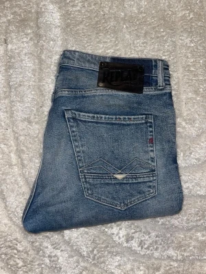 Replay jeans  - Säljer ett par Replay jeans i blå tvätt med slitningar och hål på knäna. Midja 42cm, längd 101cm. OBS storlekslappen saknas men jag uppskattar dem till W32 L32 - men utgå efter mått! JAG SKICKAR EJ FLER BILDER NÄR JAG BÄR JEANSEN! för bättre inblick i passformen rekommenderar jag att googla på modellnamnet. För storleksguide kolla måtten noggrant då jeansen alltid kan vara uppsydda heller krympta och jag ej tar emot returer :) s6,2