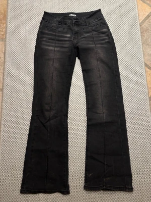 Svarta bootcut jeans från Madlady - Säljer ett par svarta bootcut jeans från Madlady med hög midja och dekorativa sömmar framtill. Jeansen har fickdetaljer fram och broderade bakfickor. Materialet är stretchigt och bekvämt, perfekt för dig som gillar en klassisk men trendig look. Storleken är 36 SHORT