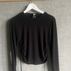 Svart långärmad topp från NLY Trend - Säljer en stilren svart långärmad topp från NLY Trend i storlek S. Toppen har en snygg öppen rygg och är tillverkad i mjukt polyester-material. Perfekt för både vardag och fest! 🖤