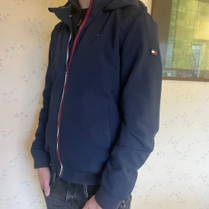 Mörkblå windbreaker från Tommy Hilfiger - Säljer en snygg mörkblå jacka från Tommy Hilfiger. Den har en dragkedja framtill och en liten logga på ärmen. Perfekt för höst och vår med sin stilrena design och bekväma passform. Jackan är i mycket bra skick och redo för nya äventyr! Storlek 176 men sitter som s jag är 182 som referens.