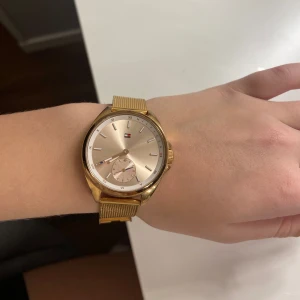 Guldfärgad klocka från Tommy Hilfiger - Säljer min guldfärgad klocka från Tommy Hilfiger. Den har ett mesh-armband och en urtavla med romerska siffror. Klockan är i rostfritt stål. Inga derfekter, Perfekt för både vardag och fest! Skriv vid fler frågor😇