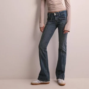 Blå bootcut jeans - Snygga blå bootcut jeans med hög midja och dubbla knappar fram. De har coola fickdetaljer och en klassisk jeanslook. 