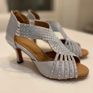 Brand new silver dance shoe with strass 38 - Endast prövade snygga dansskor i silver med strass.  Öppen tå och klack.  Dragkedja på baksidan.  Mjuk sula.  Storlek 38.  Innermått ca 24 cm, se bild.