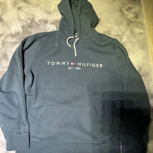 Tommy hilfiger hoodie  - stilren och bekväm tröja i högkvalitativ bomullsblandning. Den har en klassisk passform med en justerbar huva och en känguruficka fram. Den har inga fläckar eller så överhuvudtaget, vet inte riktigt vad de för färg. 