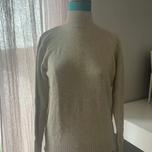 Beige polotröja - Säljer en beige polotröja i mycket bra skick.  Tröjan har långa ärmar och ribbade detaljer vid hals, ärmslut och nederkant. Passar både till vardags och lite finare tillfällen.