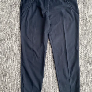 Mörkblåa byxor i strl 42 från Hugo Boss - Mörkblåa byxor i strl 42 från Hugo Boss.  Använda och visst slitage som små nopprar både på rumpan och på ena benet i övrigt i bra begagnat skick.  Mått Midjan: ca 48 cm Längd från grenen och ner: ca 73 cm  77% polyester, 20% bomull och 3% polyuretan