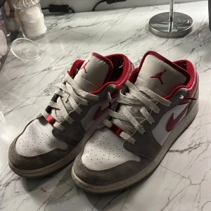 Gråa jordans low - Säljer dessa snygga grå/röda Jordans low i fint skick. Den mest synliga skadan är i hälen(se bild 3) vilket dock inte påverkar användningen eller utseendet. Ny pris 2 500kr