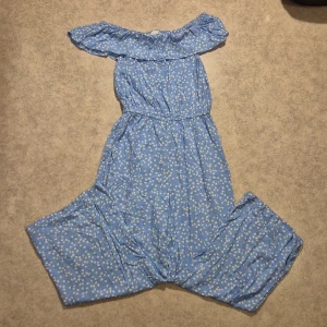 Blommig byxdress - Blommig ljusblå byxdress, går att ha off-shoulder, använd men i bra skick 