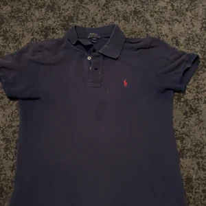Mörkblå pikétröja från Ralph Lauren - Säljer en mörkblå pikétröja från Ralph Lauren. Perfekt för både vardag och lite finare tillfällen. Passar bra till jeans eller chinos. Hör av dig vid intresse! 💙L barn