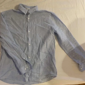 Ljusblå skjorta med knappar - Säljer en stilren ljusblå skjorta från H&M i bomull. Den har långa ärmar och klassisk krage med knappar hela vägen ner. Perfekt för både vardag och festliga tillfällen. Skjortan är i bra skick och passar till många olika outfits. 🕺storlek 152 men passar om man är 160 också.