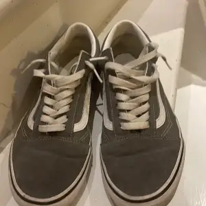 Säljer ett par grå Vans sneakers i bra skick. De har den klassiska vita sidostripen och snörning. Perfekta för vardagsbruk och ger en skön streetstyle-look. Passar till både jeans och shorts!