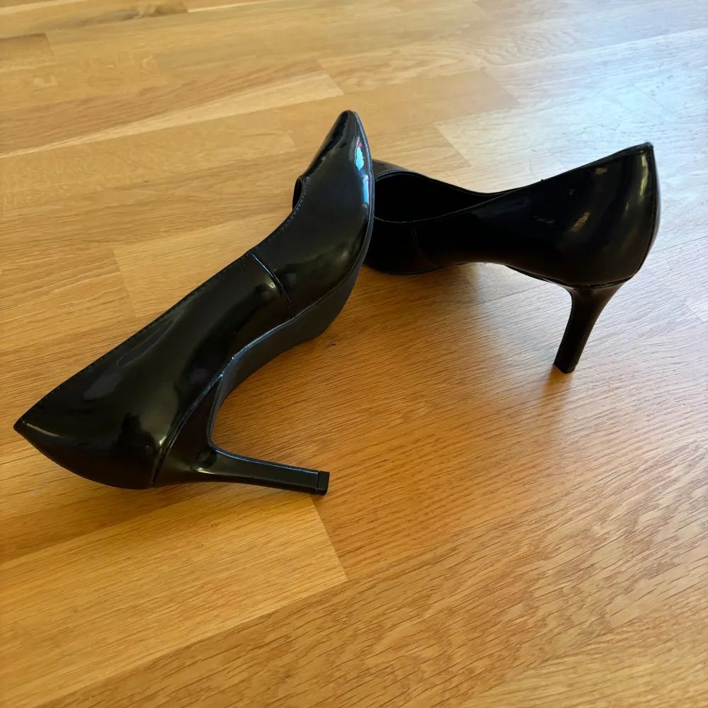 Snygga svarta pumps i mycket bra skick. De har en elegant spetsig tå och en smal klack som ger en stilren look. Perfekta för fest eller en utekväll. Materialet är glansig lack och ger en lyxig känsla. Passar till både klänning och byxor!. Skor.