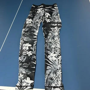 Svarta leggings med blommönster från Stronger - Snygga svarta leggings från Stronger med blommönster i vitt och grått.